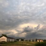 Dramatic Storm Clouds Over a Rural Farmstead with Weathered Barns and Grain Silos